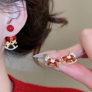 Gros plan détaillé d'une boucle d'oreille cheval à bascule doré avec émail rouge et brillants