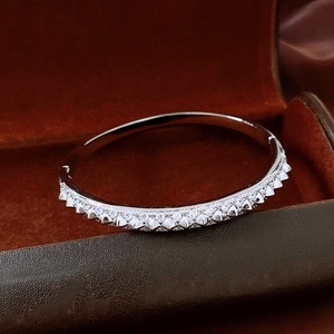 Detailed macro shot of silver rivet bracelet with cubic zirconia in a brown velvet box