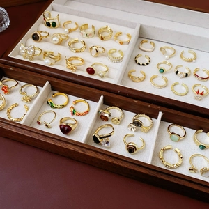 Collection de bagues dorées ajustables avec zircon et émail sur un plateau en bois