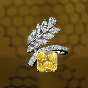 Detail of radiant cut yellow diamond ring with crystal leaf accents and pavé band