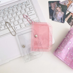 Pink and clear glitter PVC photocard holders with bead chains on a white keyboard