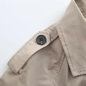 Détail d'un trench-coat kaki avec épaulettes classiques et boutons en résine noire