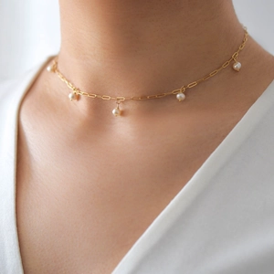 Minimalist stainless steel Figaro chain necklace with a white round pearl pendant on a model