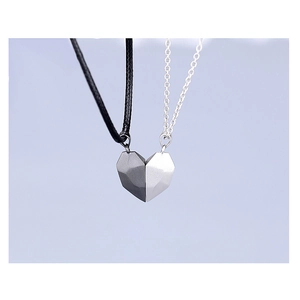 Close-up of magnetic heart pendants in silver and black on a light blue background
