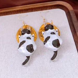 Whimsical black and white spotted cat drop earrings with yellow disk and gold hooks