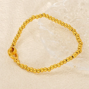 Detailed view of a golden bead chain bracelet featuring a unique OT clasp closure