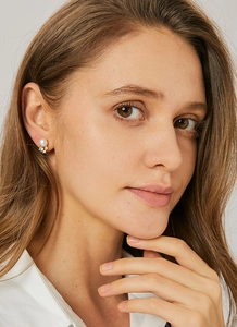 Detail view of pearl earrings with zircon cluster accents on model's ear in gold finish