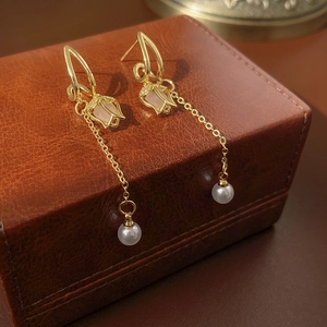 Gros plan détaillé de boucles d'oreilles tulipes dorées avec perles sur boîte en cuir