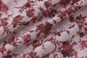 Detail des dunkelroten Blumenmusters auf leichtem Stoff mit weichen Falten und Textur