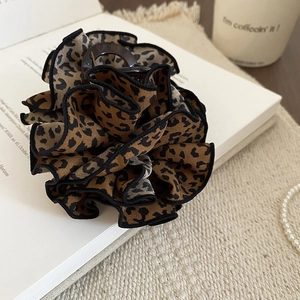 Detail of leopard print fabric hair claw clip with pleated texture on white background