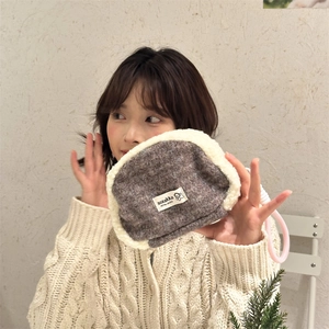 Detail of plush tweed cosmetic shell bag featuring soft faux shearling trim and woven lanyard