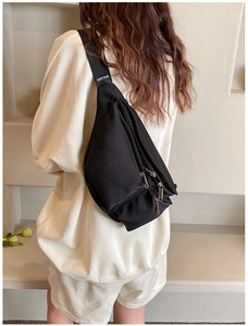 Detail of adjustable wide shoulder strap on a black nylon crossbody sling bag