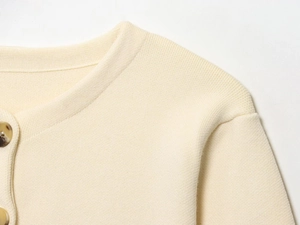 Macro detail of cream knit cardigan featuring marble texture buttons and ribbed collar