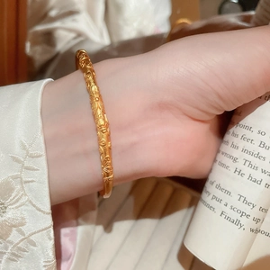 Detail of floral embossed gold bracelet worn on wrist with elegant embroidered sleeve