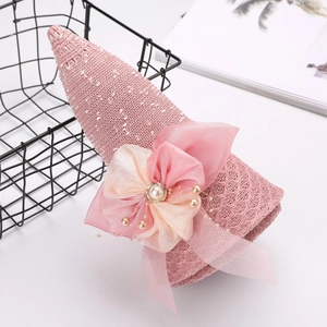 Dettaglio cappello da sole rosa in maglia con grande fiocco in organza e perle bianche