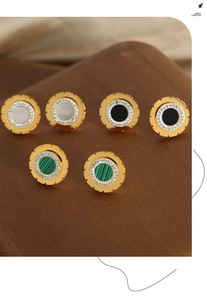Close-up of gold-plated gear earrings with inset stones and sparkling zircon details