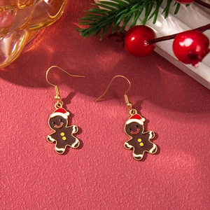 Detail of gingerbread man Christmas earrings with alloy drip oil on festive red background