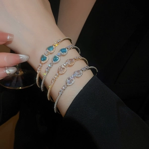 Detail view of heart-shaped zircon bracelet with blue and white crystals in gold finish