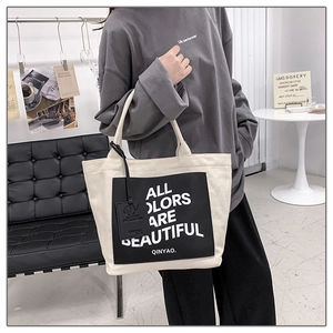 Detail of canvas tote bag featuring ALL COLORS ARE BEAUTIFUL text and leather tag