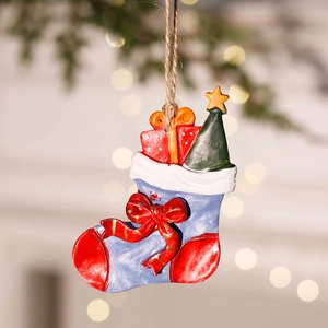 Close-up of a blue resin Christmas stocking ornament with tree and gift on light background