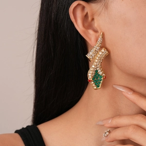 Close-up of snake earrings with green rhinestones and gold plating on female model