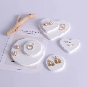 Minimalist geometric jewelry display stand with golden rings and pearl earrings on plaster