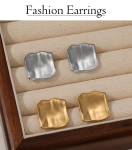 Detail of square irregular metal stud earrings in a beige velvet jewelry box