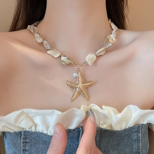 Detail of a shell pearl necklace with a gold starfish pendant in a bohemian beach style