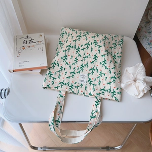 Floral cotton canvas tote bag with green leaves and orange flowers on a white table