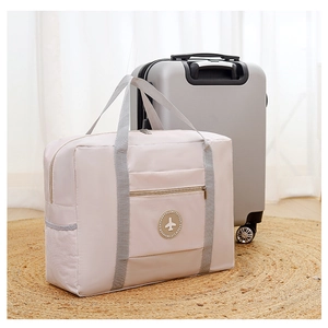 Macro detail of beige travel bag with grey handles on a straw mat by a silver suitcase