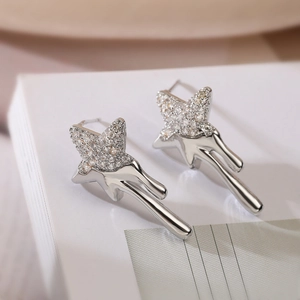 Silver star and moon stud earrings with zircon crystals on a white book background