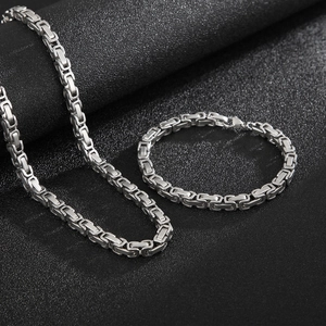Macro shot of silver stainless steel box chain necklace and bracelet set on black background