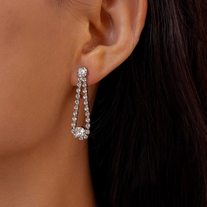 Close-up of elegant silver teardrop earrings with crystals worn by a model