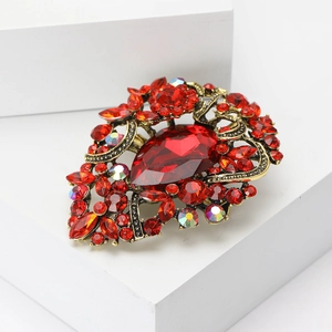 Macro shot of vintage heart brooch with red gems and ornate gold alloy texture