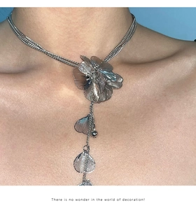 Detail of silver layered chain necklace with oversized floral pendant and fringe charms