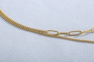 Macro detail of gold layered mixed Cuban and textured paperclip chain necklace links
