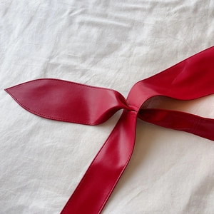 Détail de la ceinture corset en similicuir rouge vif montrant les coutures de précision