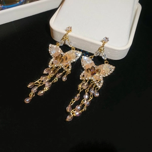 Macro shot of gold butterfly tassel earrings with champagne crystals on black velvet