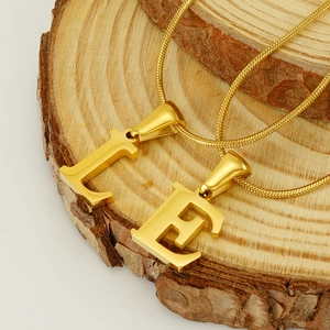 Golden titanium steel snake chain necklace with letters L and E on a natural wood piece