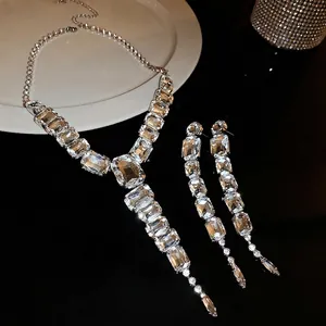 Luxury silver jewelry set with emerald-cut crystals and long tassel earrings on black mirror