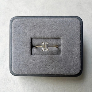 Macro view of emerald-cut moissanite ring set in a premium navy velvet jewelry gift box
