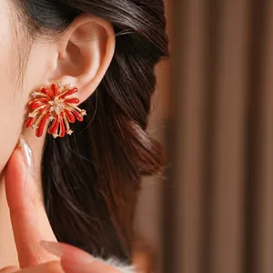 Elegant gold flower fireworks stud earrings with red enamel and sparkling zircons