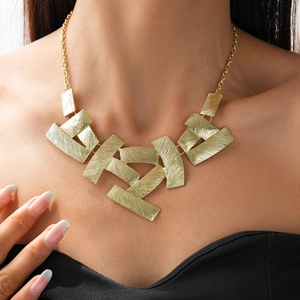 Detail of gold geometric square pendant necklace with brushed metal texture on a model