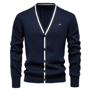 Dettaglio del cardigan con scollo a V, bordo a righe bianche e verdi e maglia blu scuro