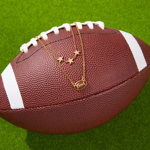 Collana a doppio strato in acciaio dorato con ciondoli a stella e rugby su erba