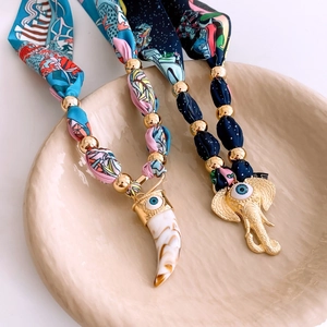 Detailed view of printed silk cord necklaces with evil eye horn and elephant charms