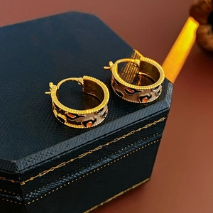 Detail of vintage gold plated hoop earrings with leopard print enamel texture