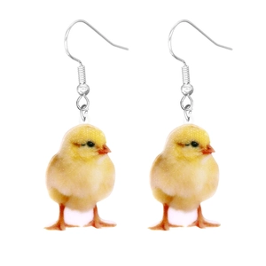 Detailed close-up of cute yellow chick acrylic earrings with silver hooks on white background