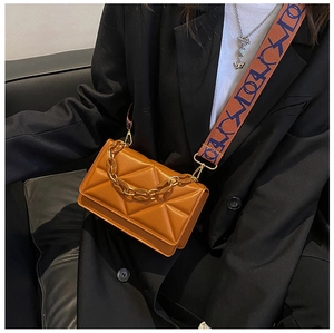 Detail of caramel quilted crossbody bag with gold chain and geometric wide strap