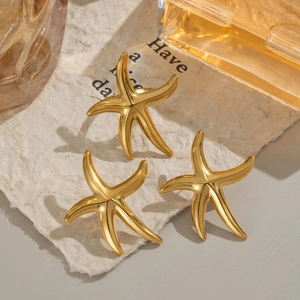 Detailed view of three gold starfish stud earrings arranged on textured vintage paper